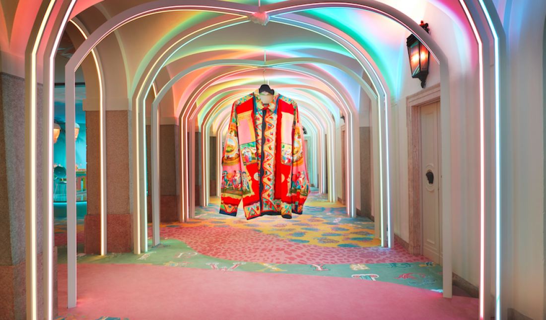 Colorful hallway with neon lights, featuring a large patterned coat hanging in the center.