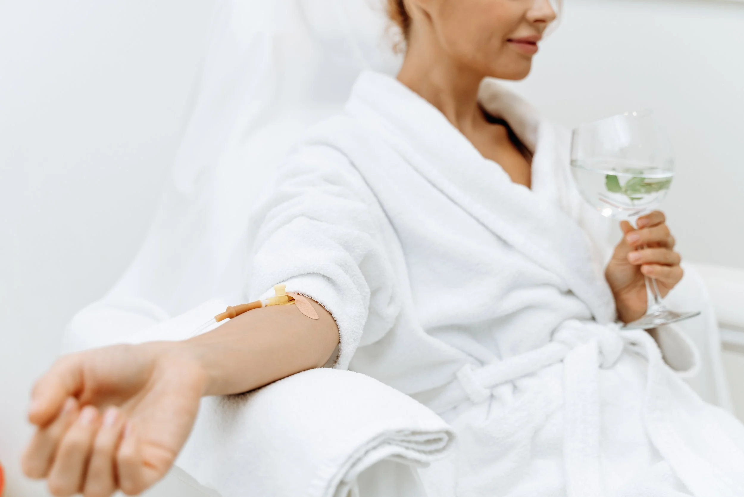 close-up-calm-female-patient-sitting-with-tube-needle-iv-infusion-girl-holding-glass-with-lemon-water-relaxing.jpg