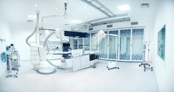 Sala de cirurgia moderna com equipamentos médicos, incluindo cadeira cirúrgica, monitores e máquinas de anestesia.