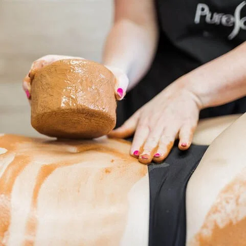 Person performing ice sculpting on a client's abdomen.