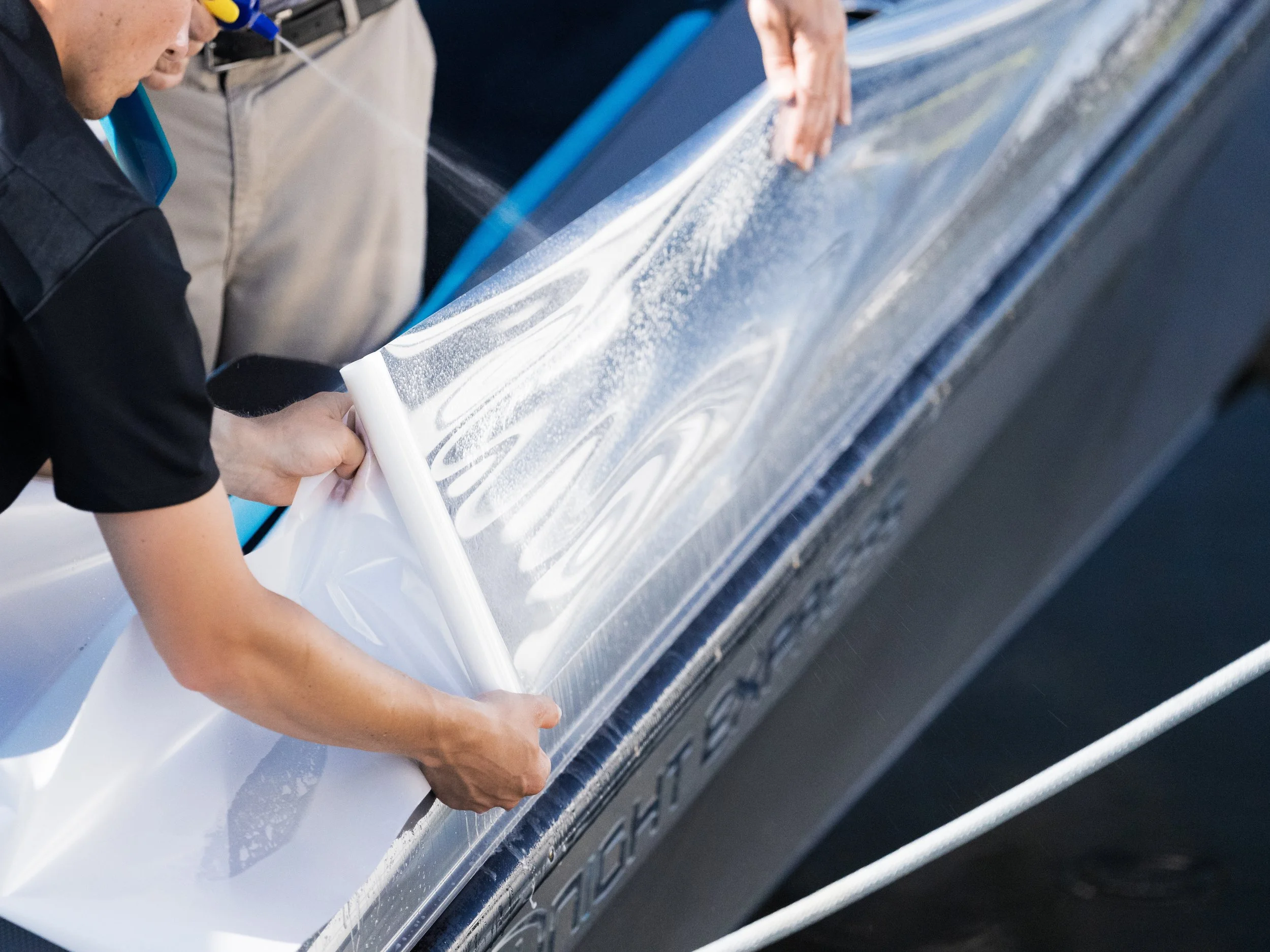 Person applying a vinyl decal or label on a car's side panel
