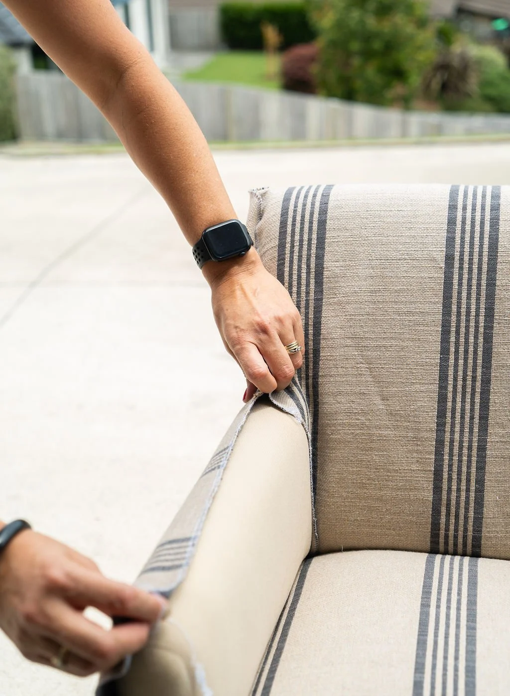 Chelsea replacing upholstery fabric on a striped armchair outdoors.