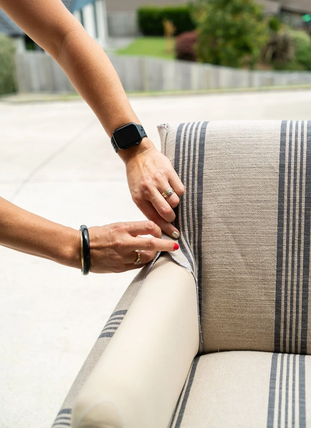 Chelsea replacing upholstery fabric on a striped armchair outdoors.
