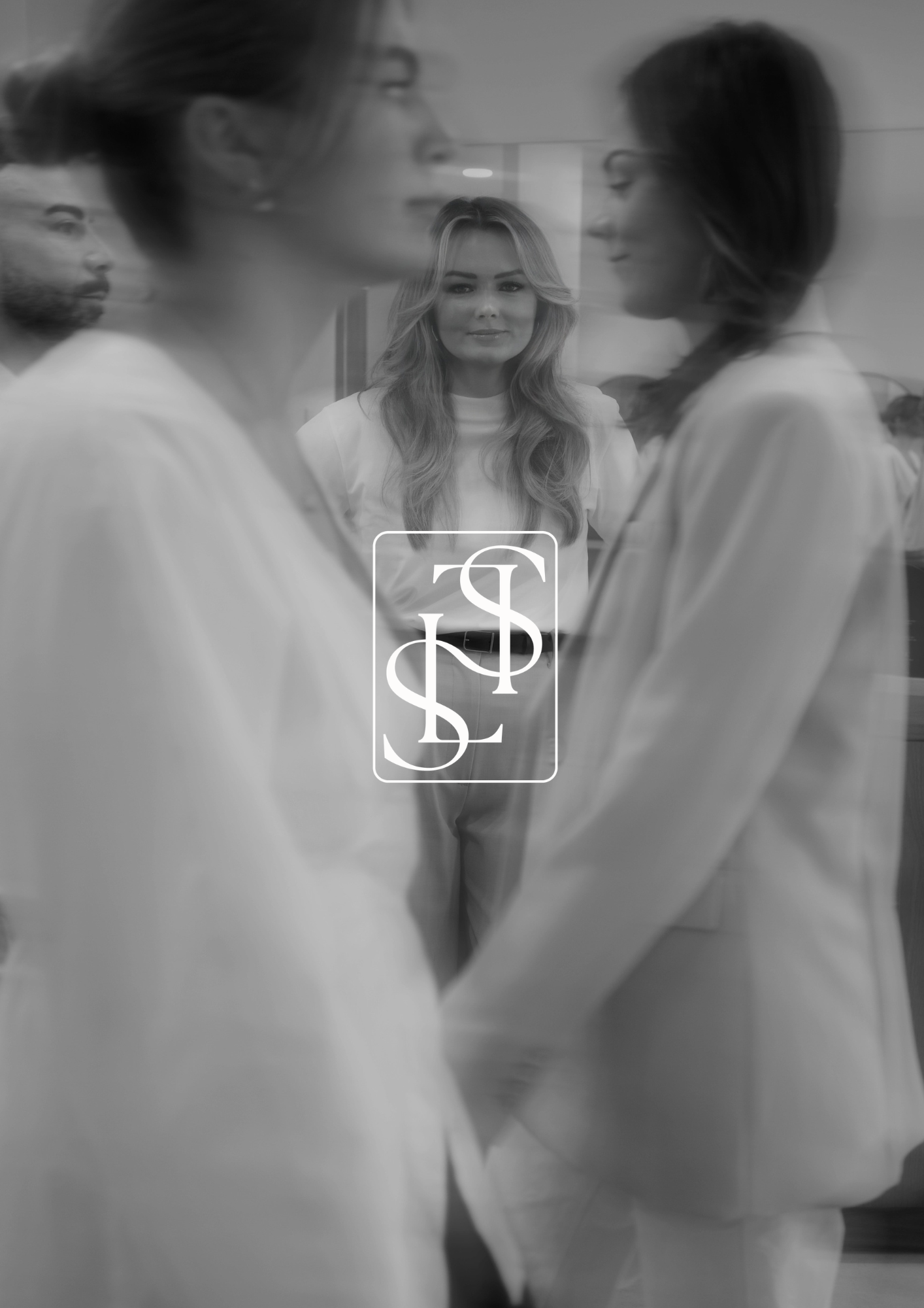 Black and white photo of two women in conversation, with a third woman standing behind a glass or mirror, observing them.