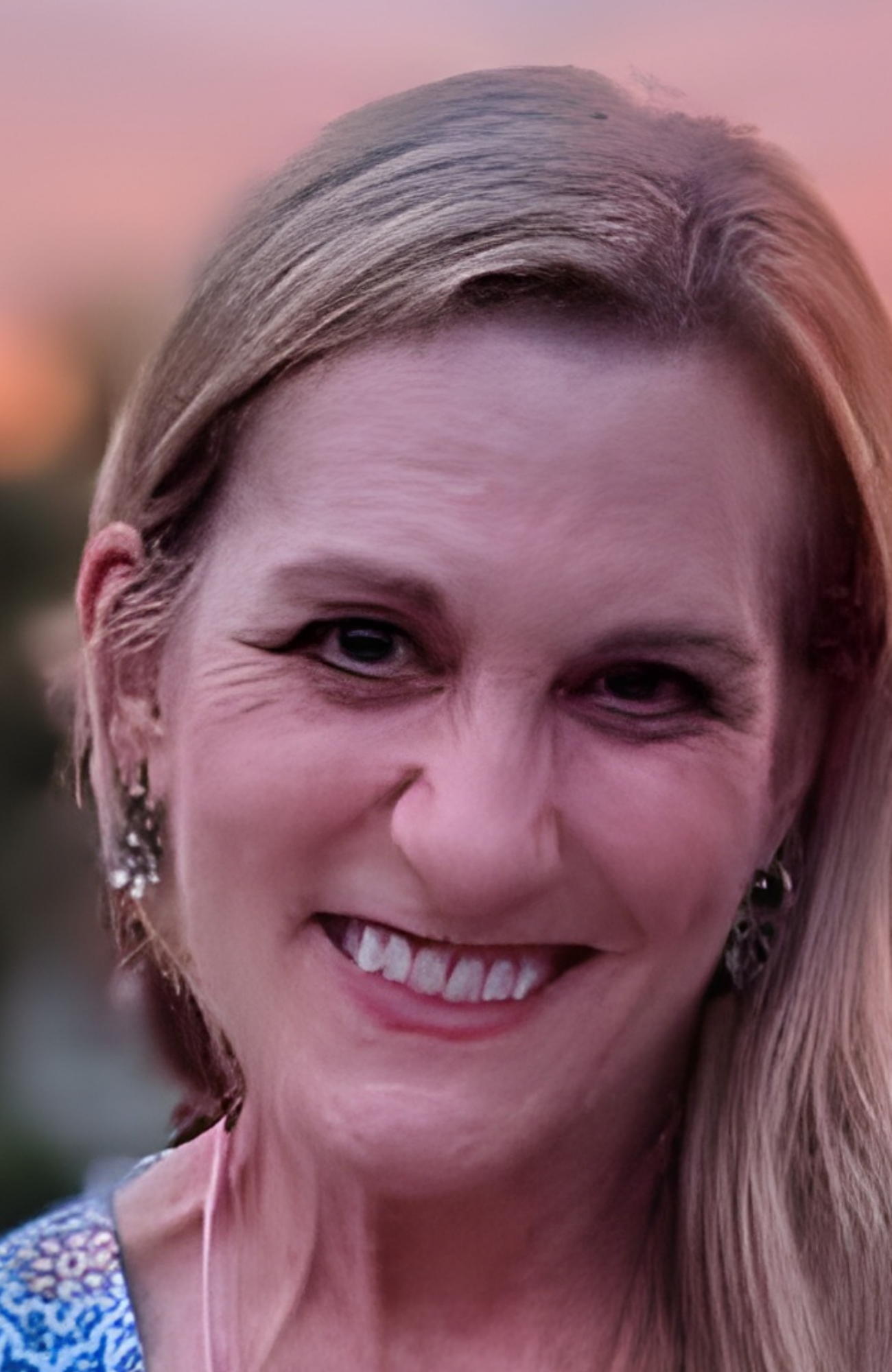 Portrait of a smiling woman with blonde hair wearing a turquoise top