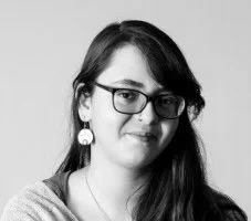 Black and white photo of a woman with long hair, glasses, and large earrings.