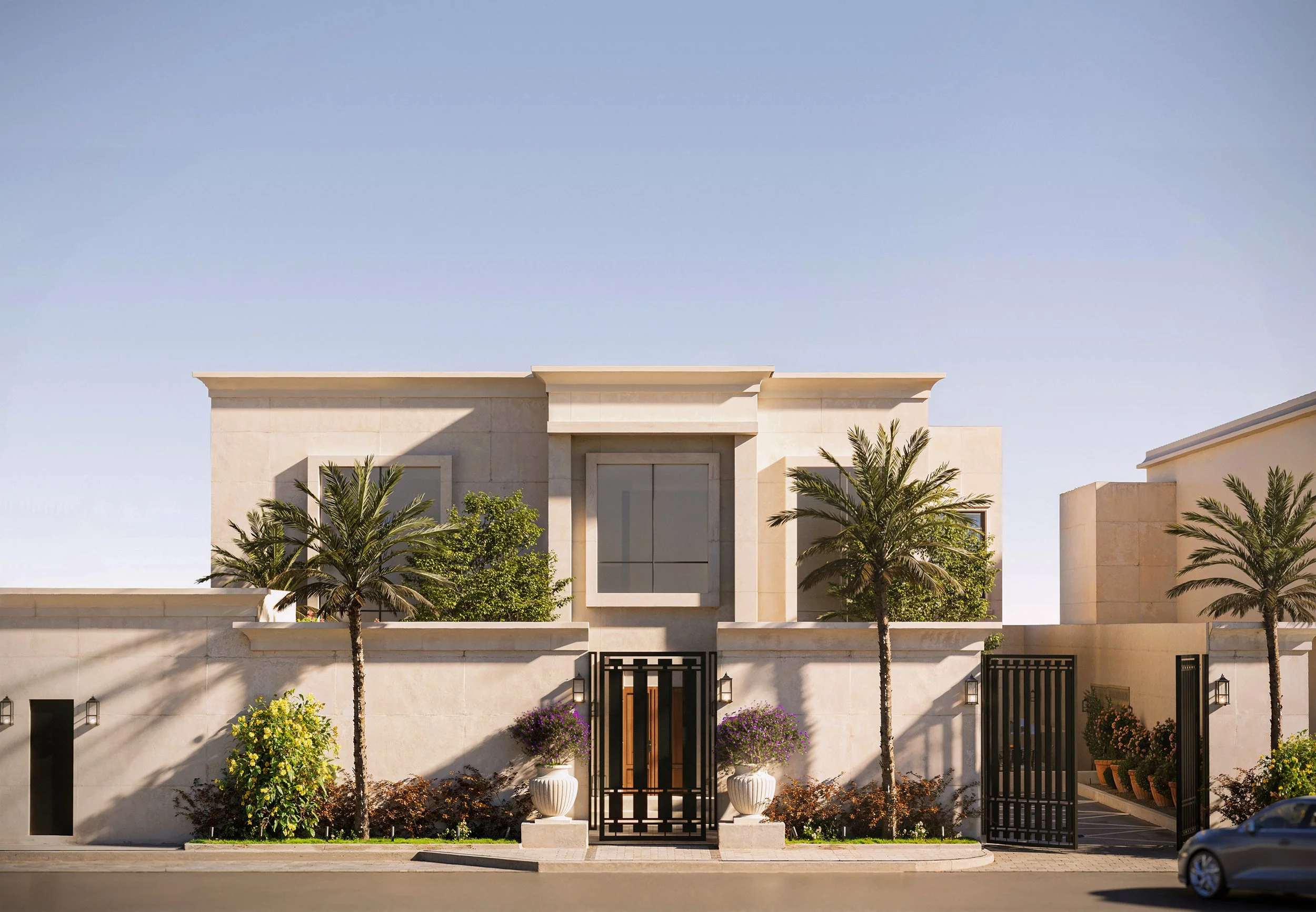 Modern beige house with a flat roof, palm trees, and potted plants in front. Black gate and clear blue sky.