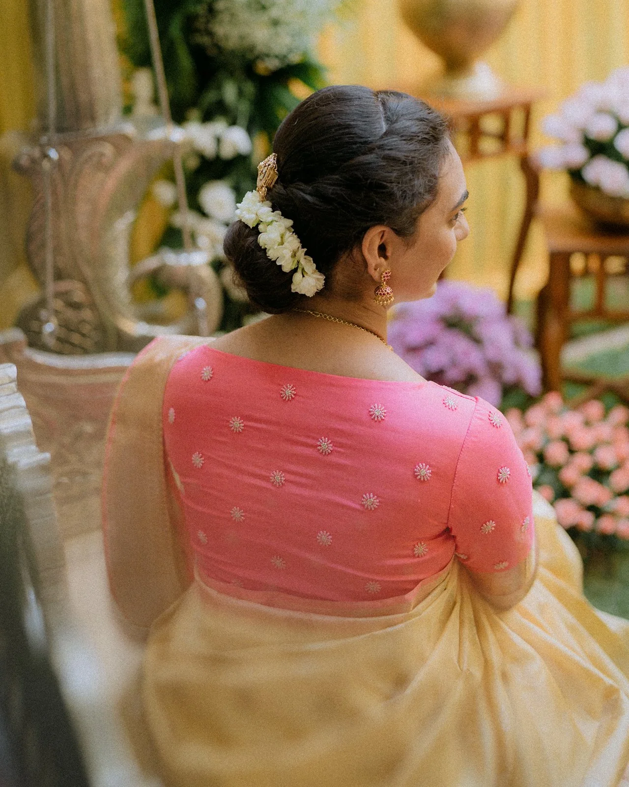 Shrishti in her haldi saree, jasmine in her hair, looking over her shoulder
