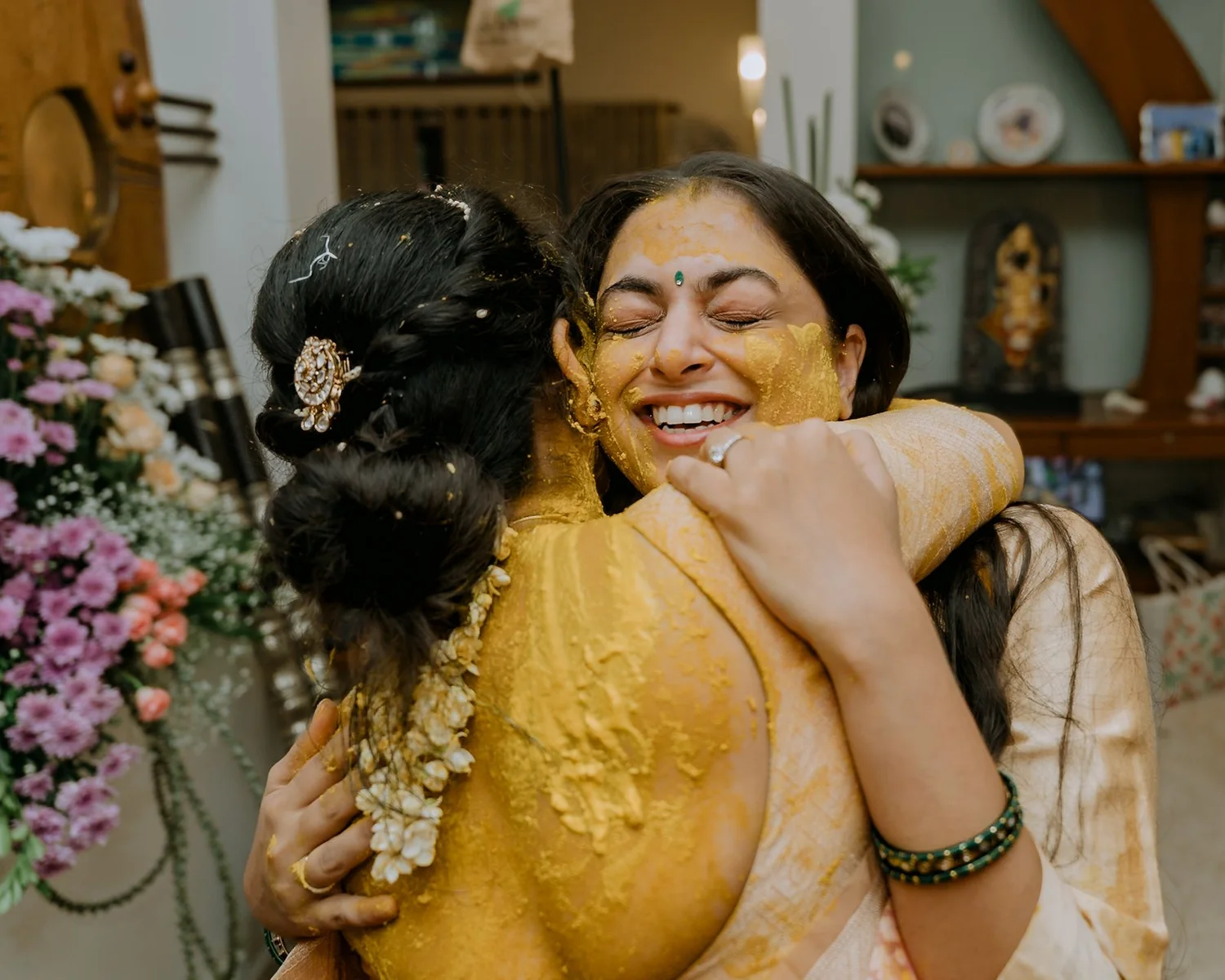Close hug at the haldi, both faces smeared with turmeric