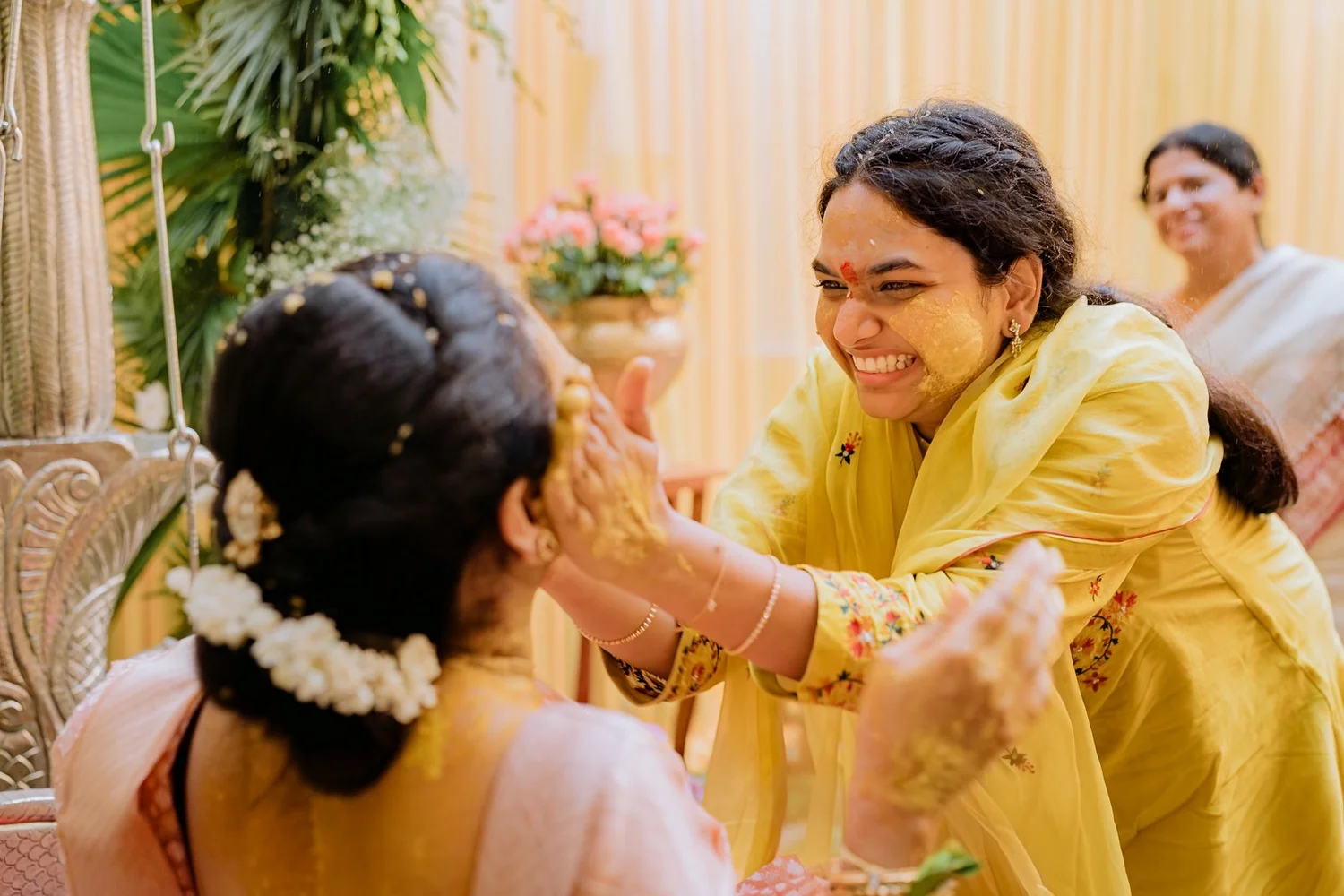 Cousin smearing haldi on the bride's face