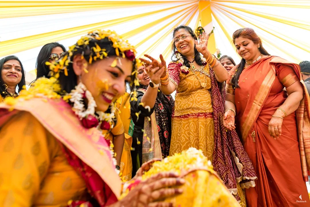 Indian bride and women celebrating at a traditional wedding ceremony, decorated with flower garlands and wearing colorful sarees.