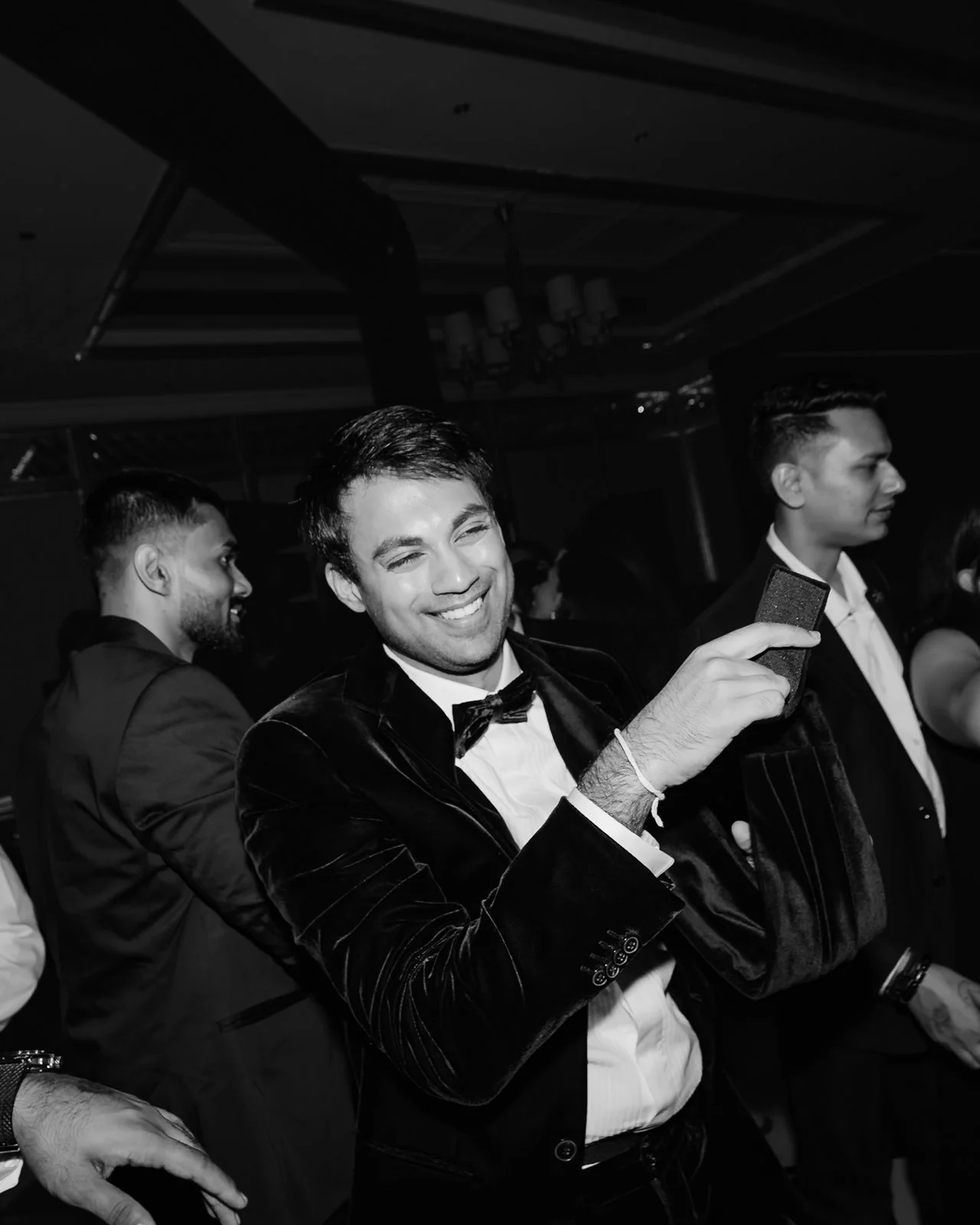 Akhil laughing with friends on the dance floor, black and white