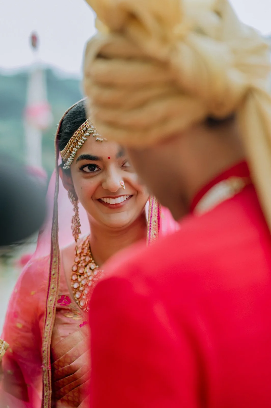 Shrishti smiling over Akhil's shoulder in his red bandhgala