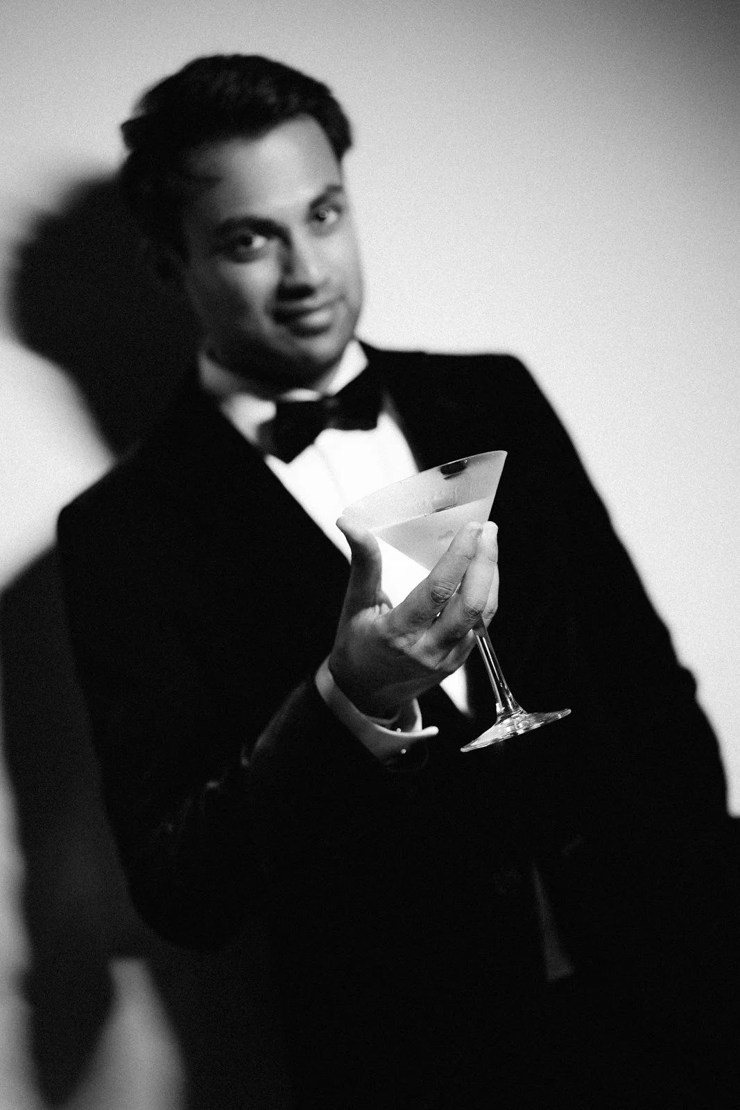 Akhil holding a cocktail glass, black and white