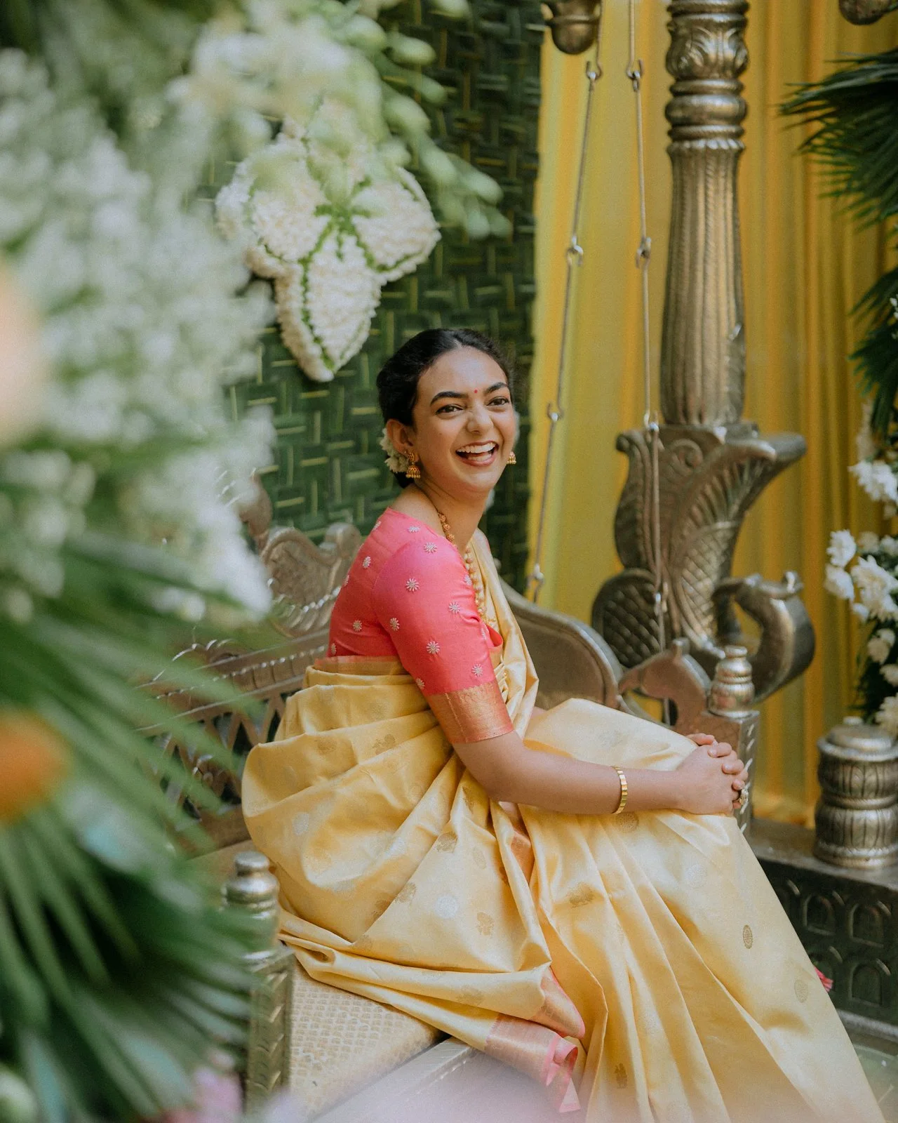 Shrishti laughing on the haldi swing in a yellow and pink saree