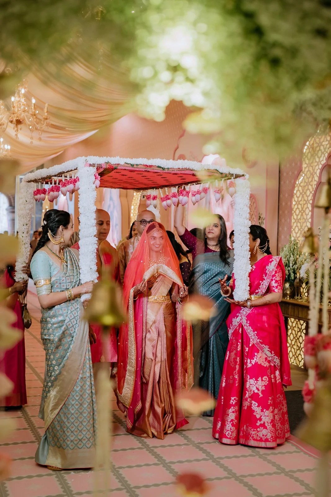 Bride entering the hall under a flower canopy with bridesmaids
