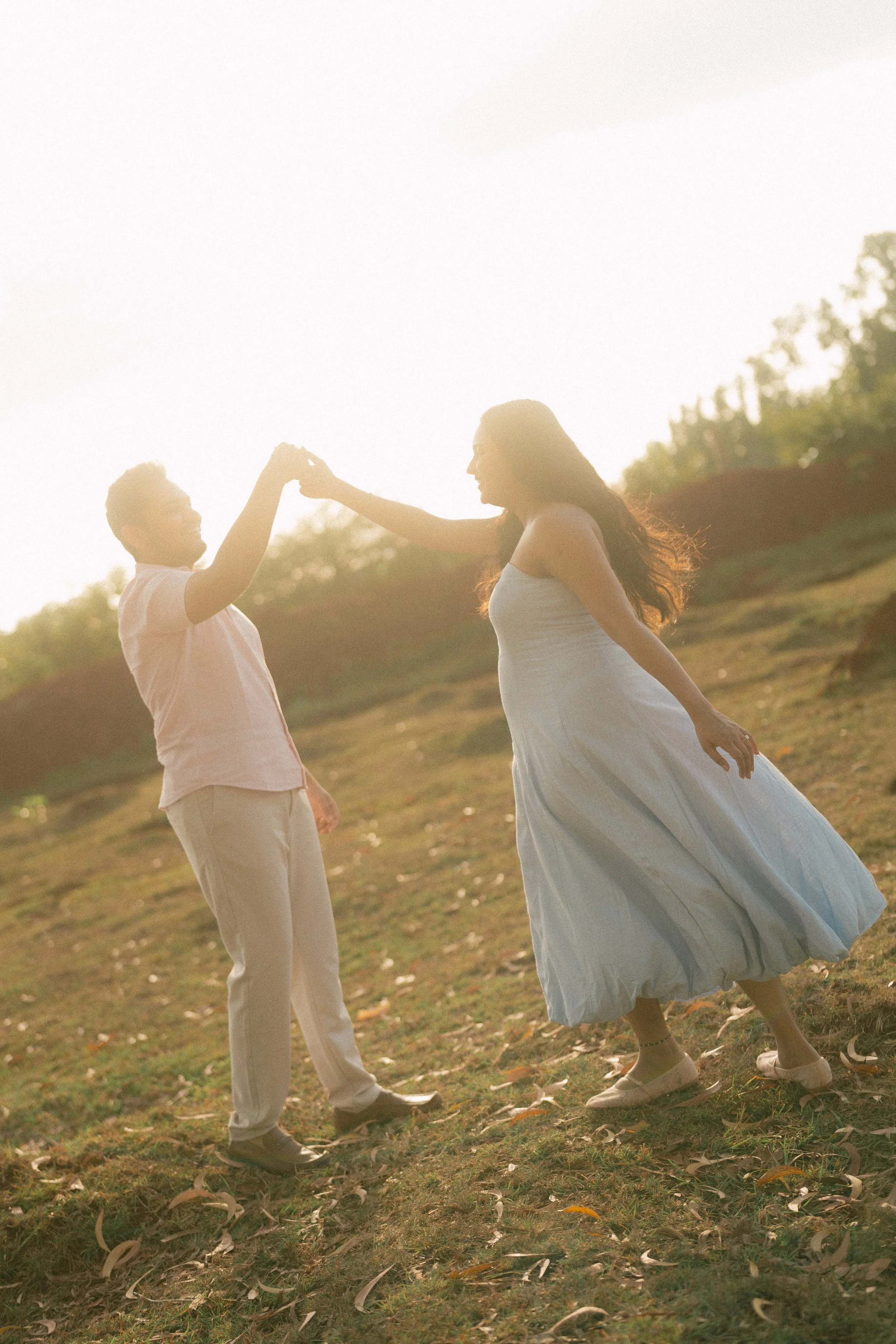 Couple dancing on a sunlit hillside, her blue dress swirling