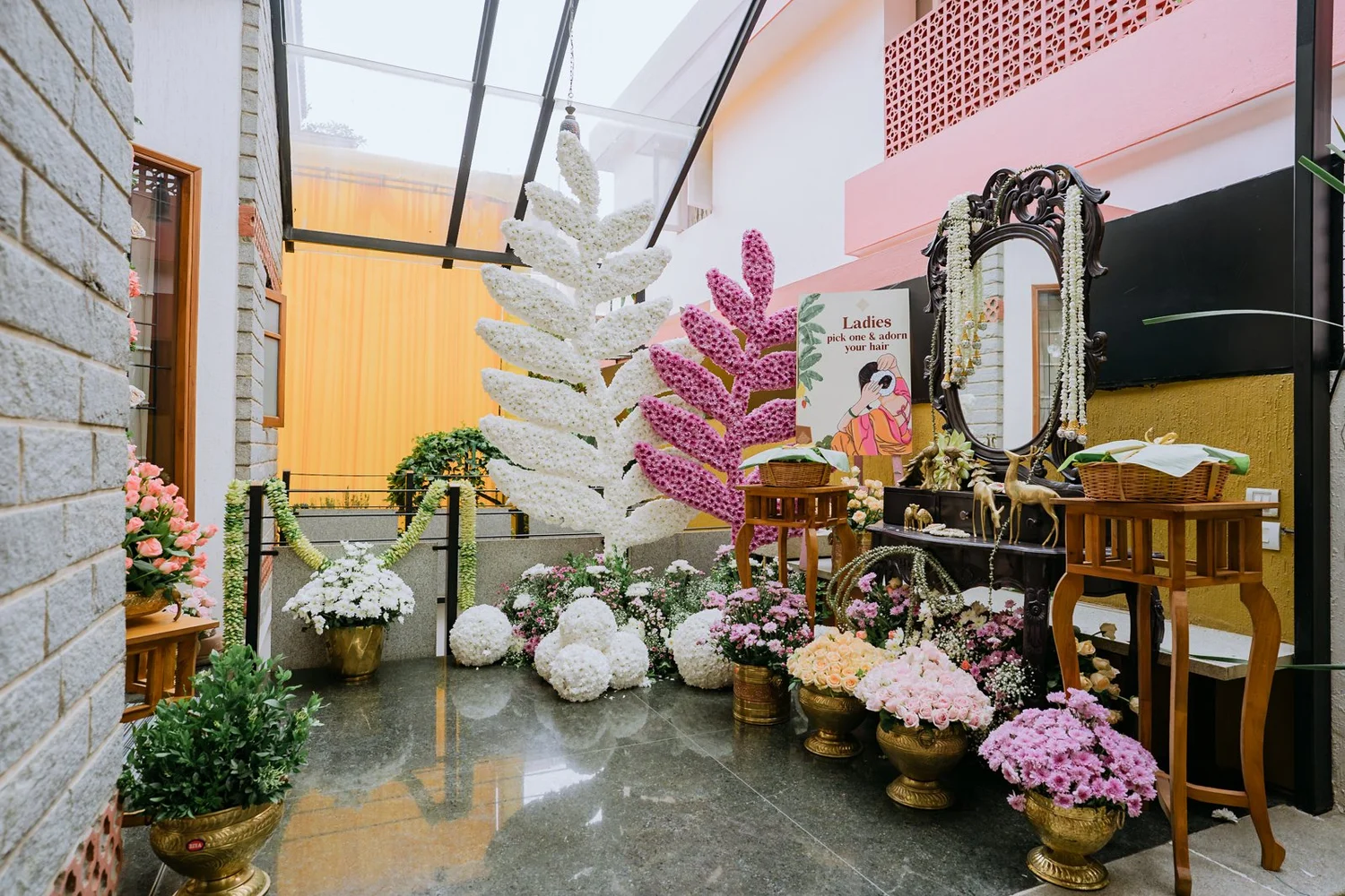Floral haldi decor with a carved mirror and potted flowers at Shrishti's home in Bengaluru