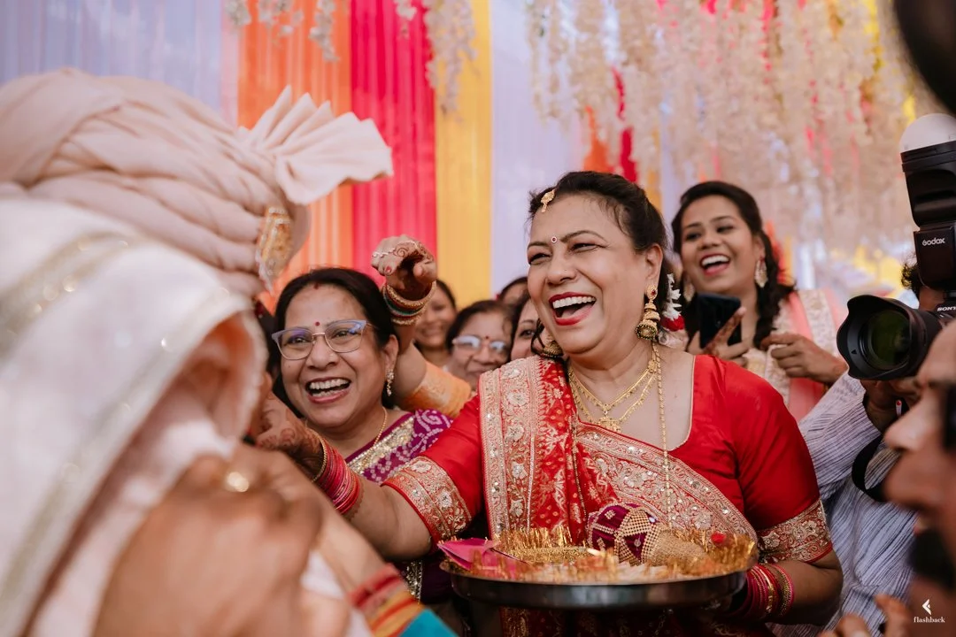 Women dressed in traditional Indian attire celebrating at a wedding event, smiling and sharing joy.