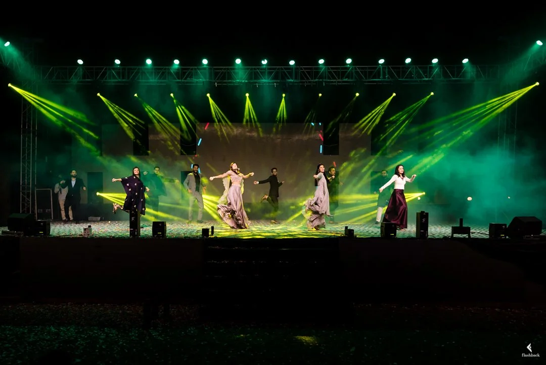 Group of performers dancing on stage under green and yellow stage lights