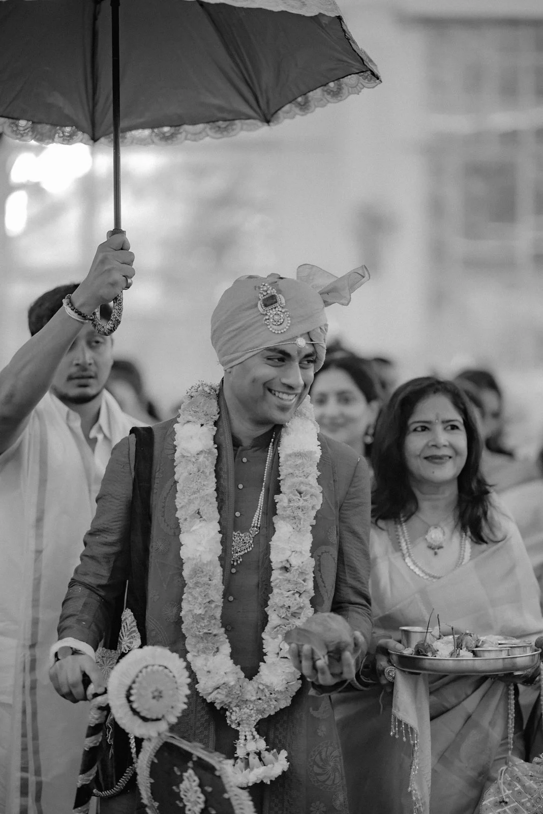 Groom laughing under the umbrella with garlands, black and white