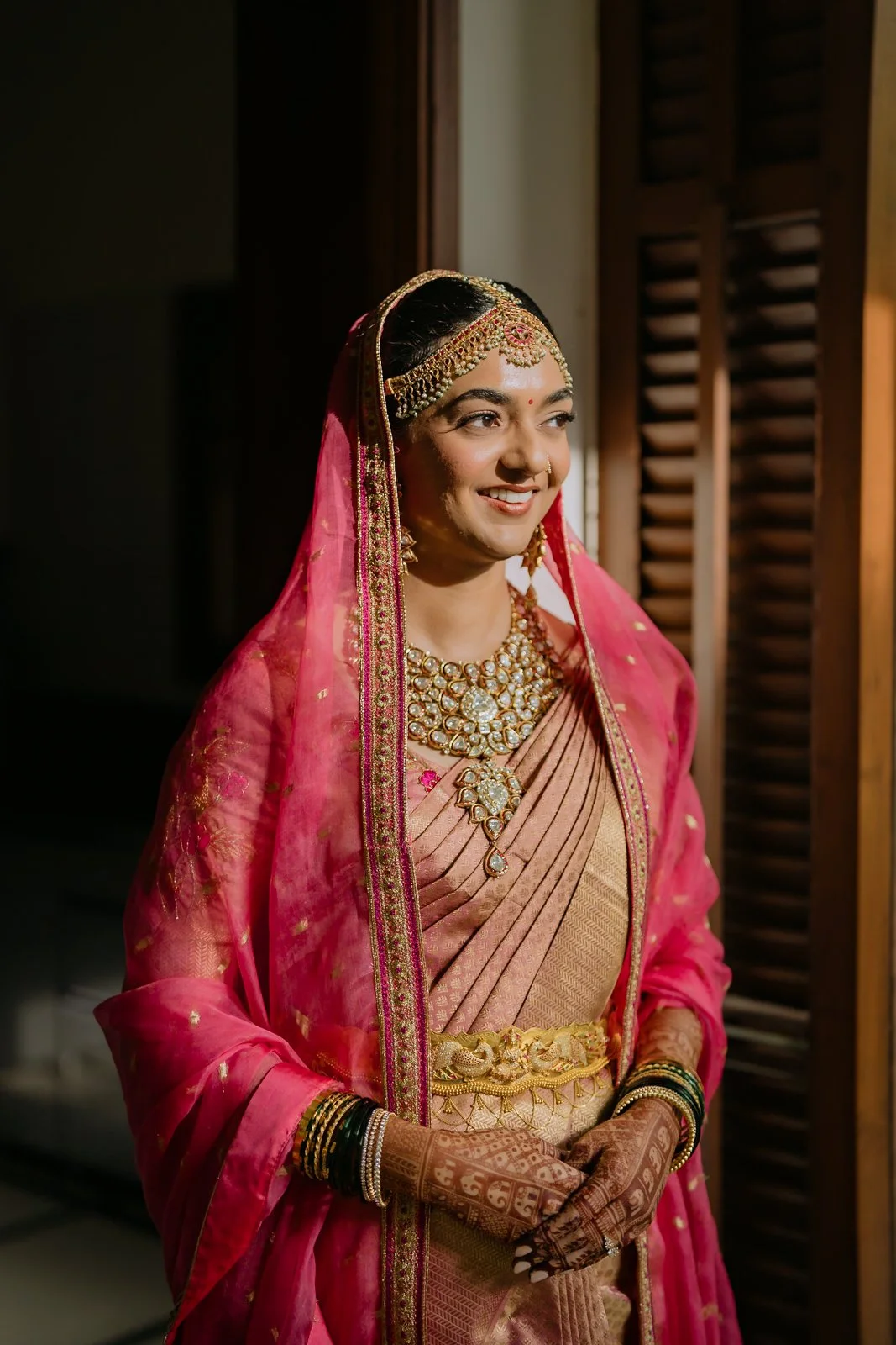 Bridal portrait of Shrishti in a pink veil by a window