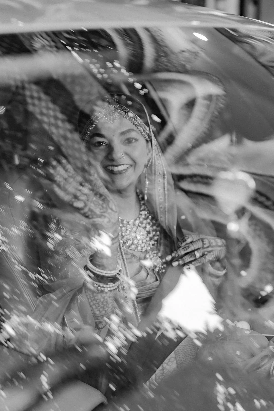 Shrishti smiling through the car window on her way to the palace, black and white