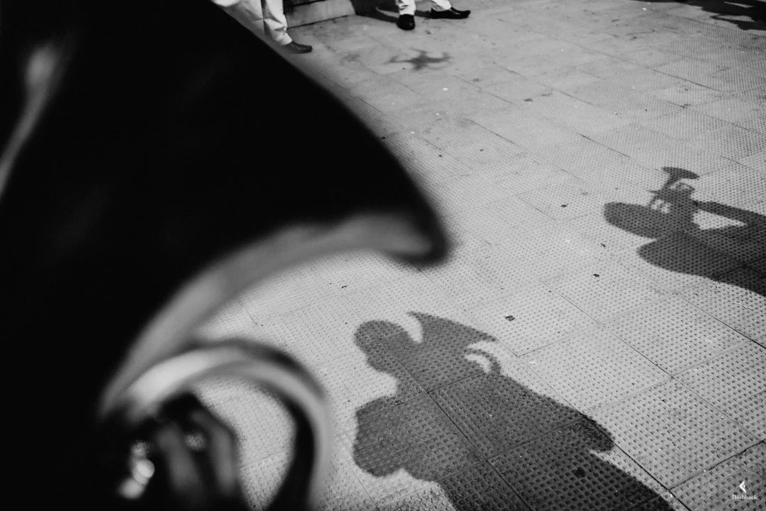 Shadow of a person riding a motorcycle cast on a tiled sidewalk.