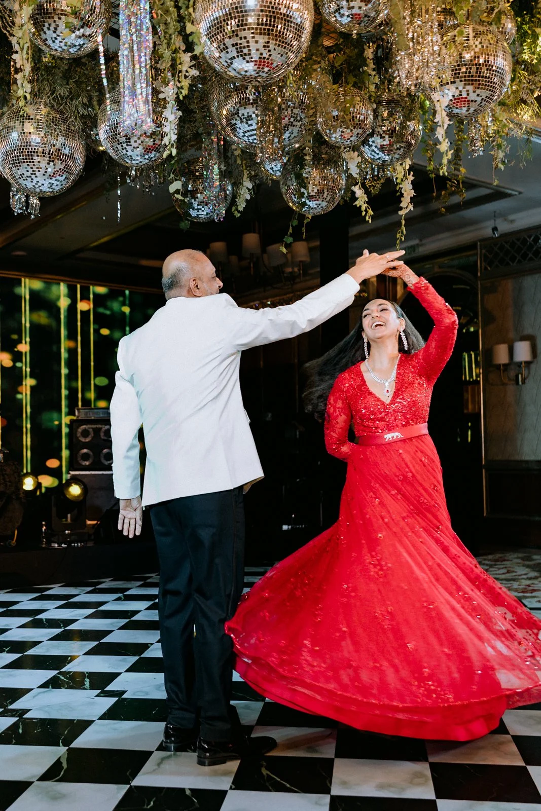 Shrishti twirling in her red gown with her father