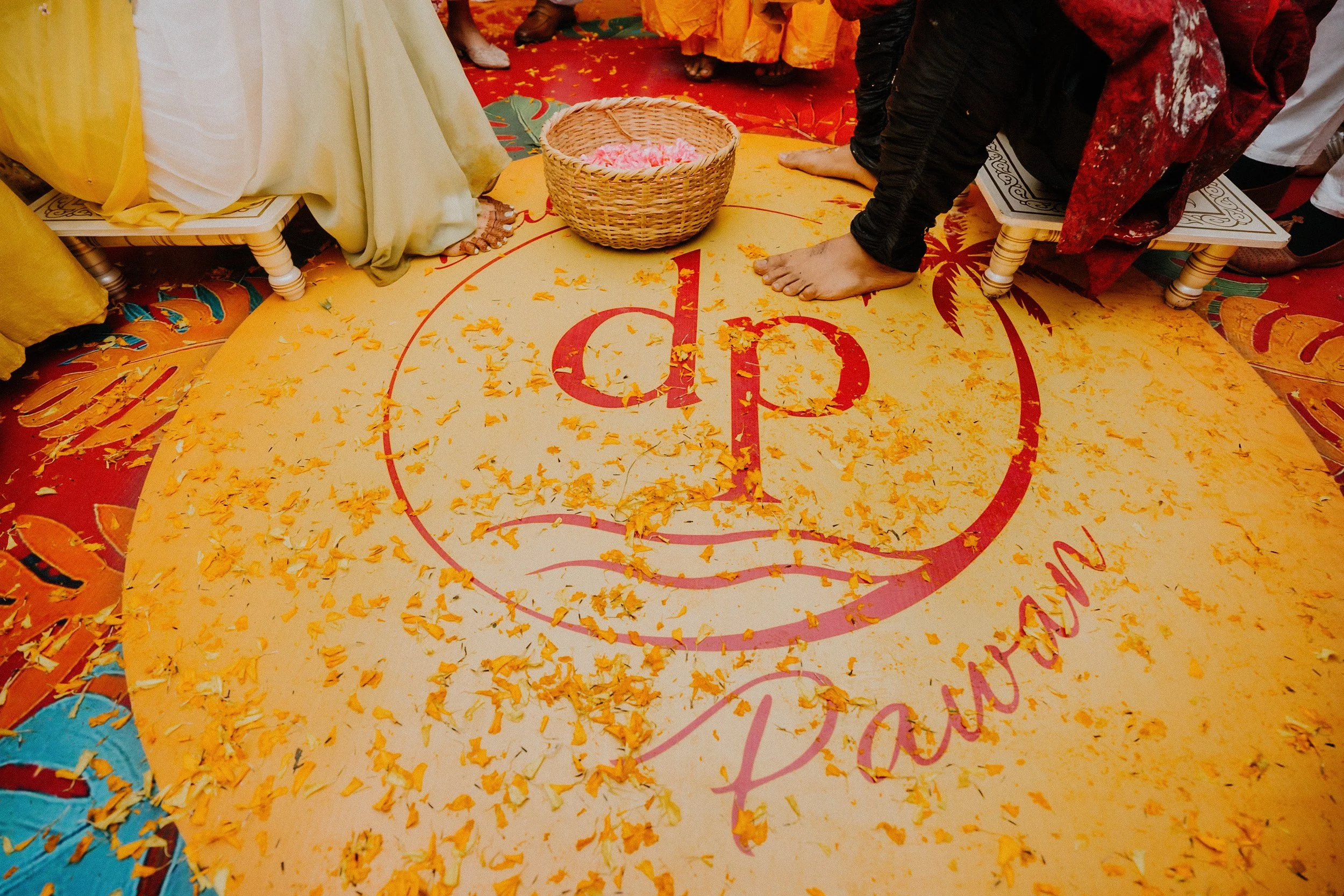People participating in an Indian wedding ritual, standing on a decorated symbolic court with flower petals scattered around.