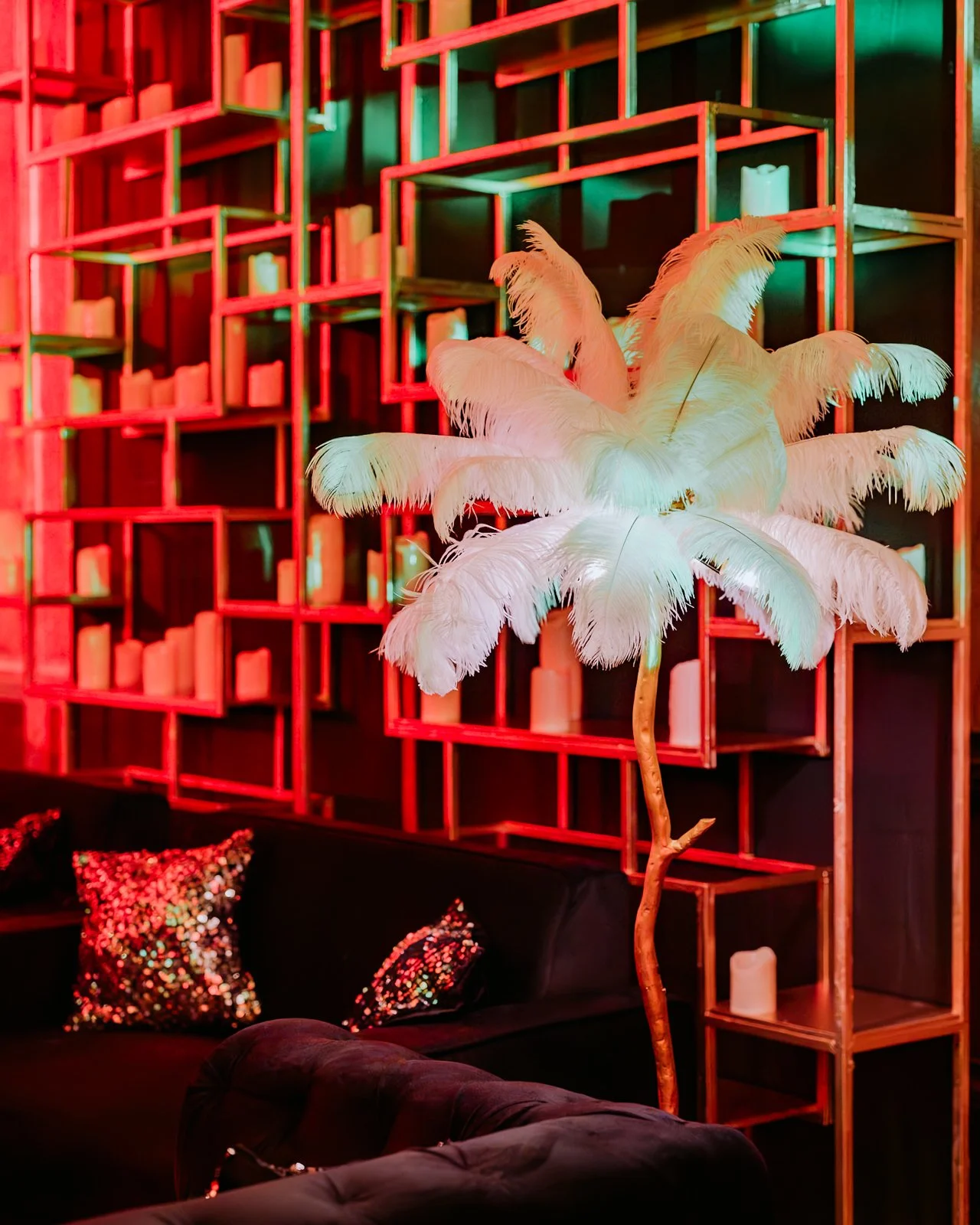 White feather installation against red shelving at the cocktail