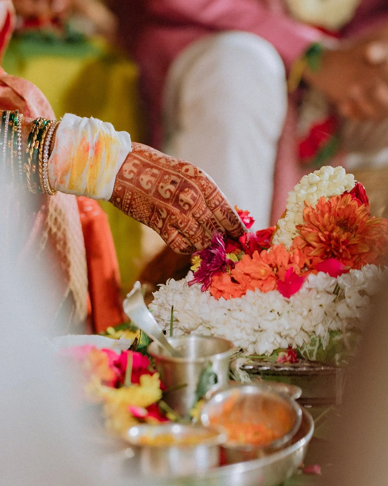 Hennaed hand placing flowers during a ritual