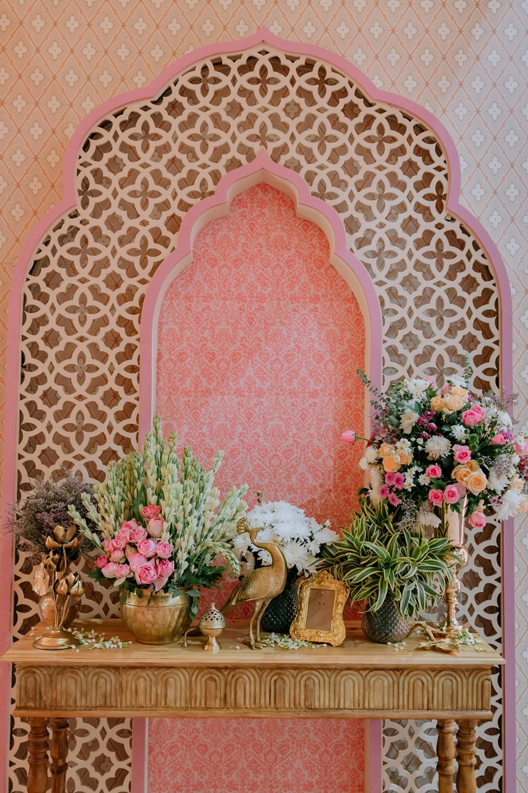Pink jaali alcove with brass vessels and flowers