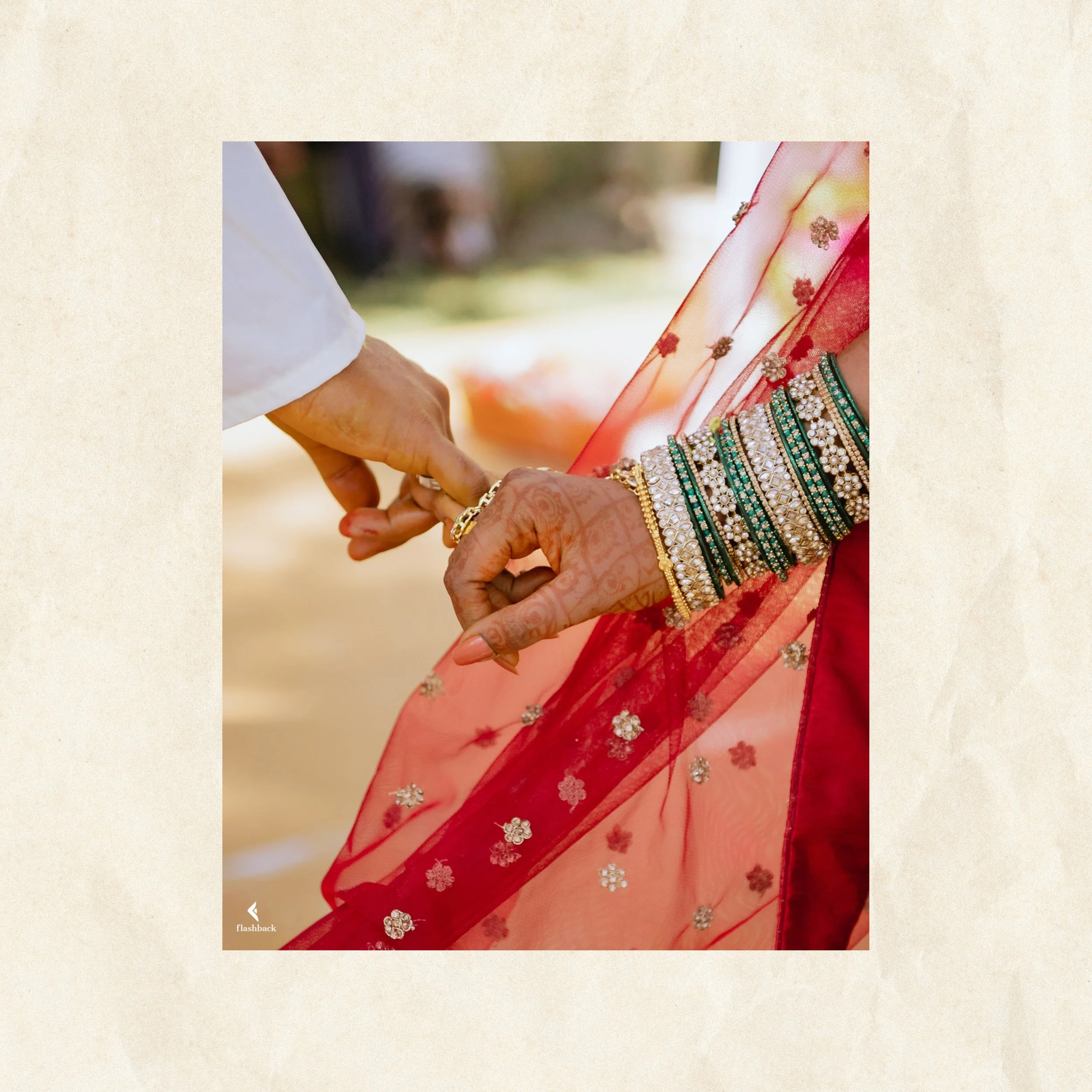 Close-up of a hand adorned with multiple green and gold bangles, holding another person's hand dressed in traditional Indian attire with henna designs, during a wedding or ceremonial event.