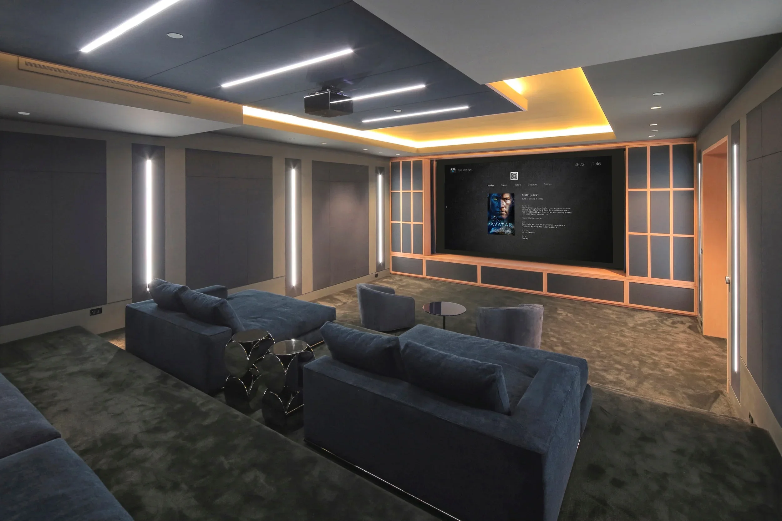 Modern home theater with dark walls, blue velvet sofas, a large screen displaying the movie Avatar, and sleek lighting fixtures.