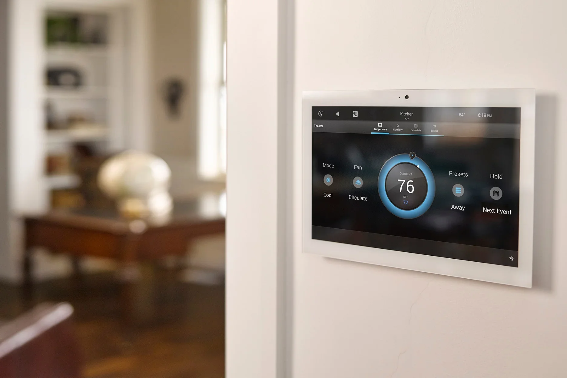 Smart thermostat on a wall displaying a temperature of 76°F in the kitchen.