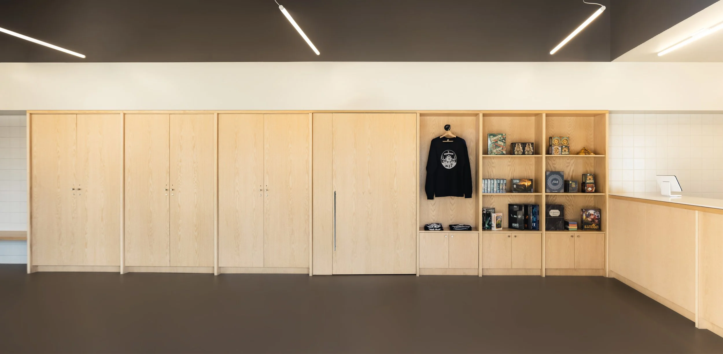 Wall of custom cabinetry showing integrated pivot door at Escape City commercial interiors tenant improvement in Calgary, Alberta