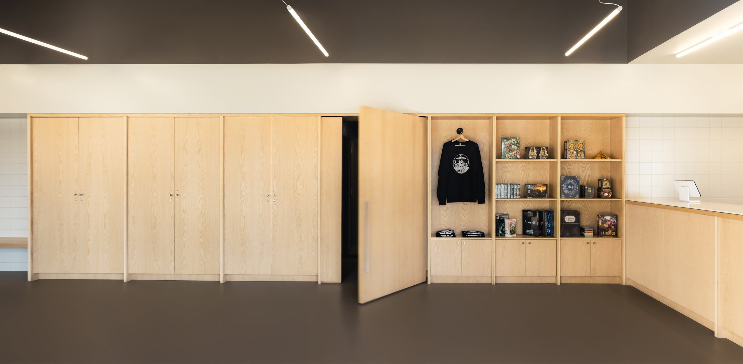 Wall of custom cabinetry showing integrated pivot door at Escape City commercial interiors tenant improvement in Calgary, Alberta