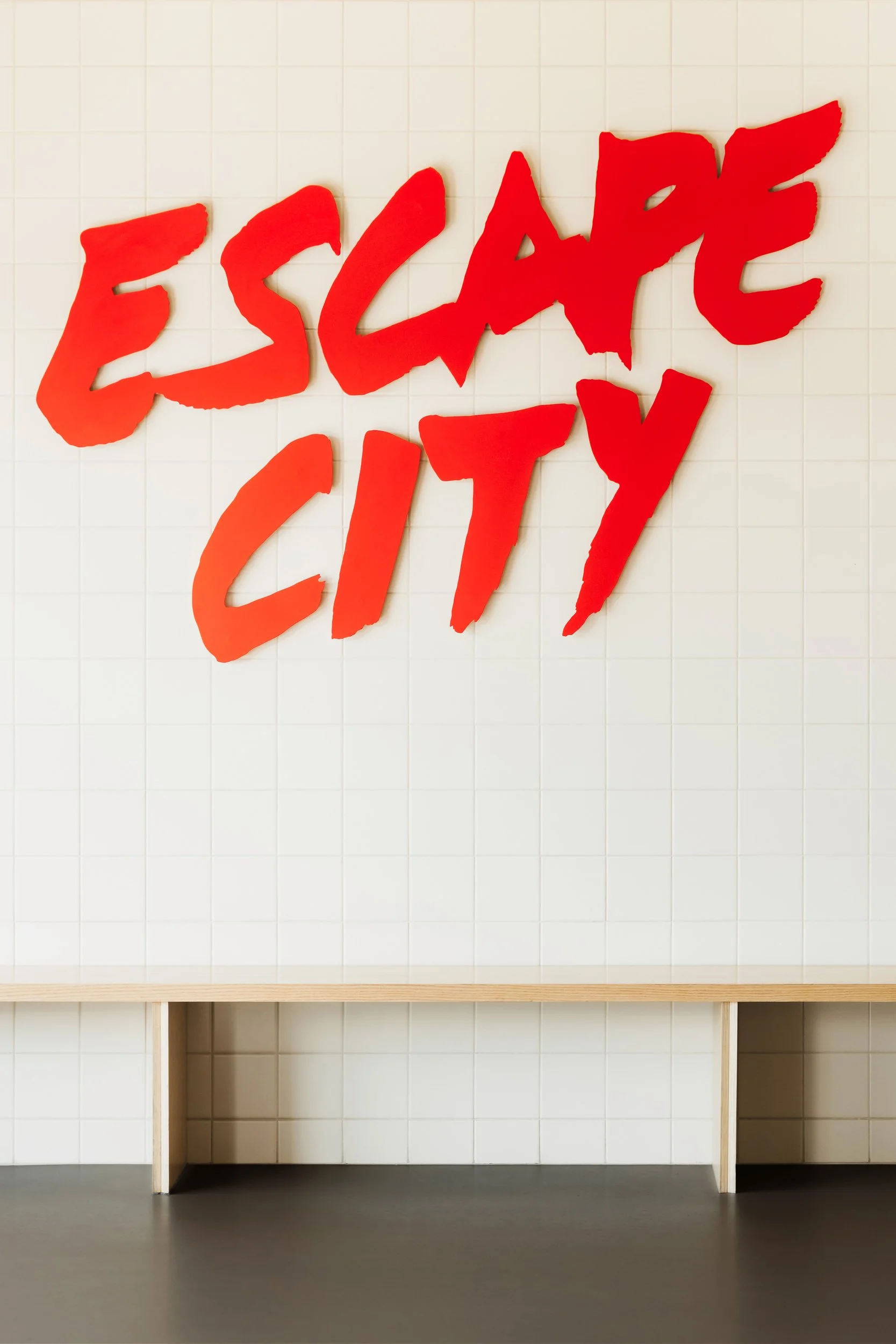 Custom metalwork sign with tiled wall and custom millwork bench at Escape City commercial interiors tenant improvement in Calgary, Alberta