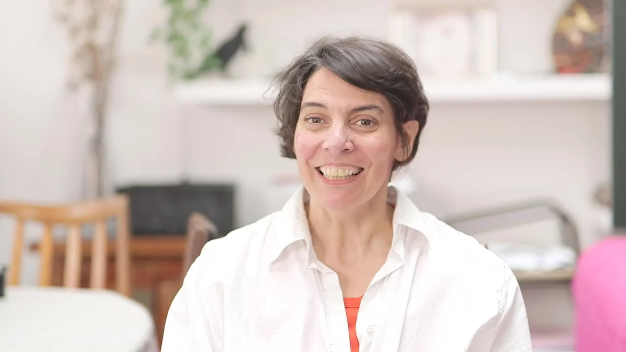 A woman named Luna who lives with Multiple Sclerosis smiling at the camera her face filled with joy wearing a white shirt.
