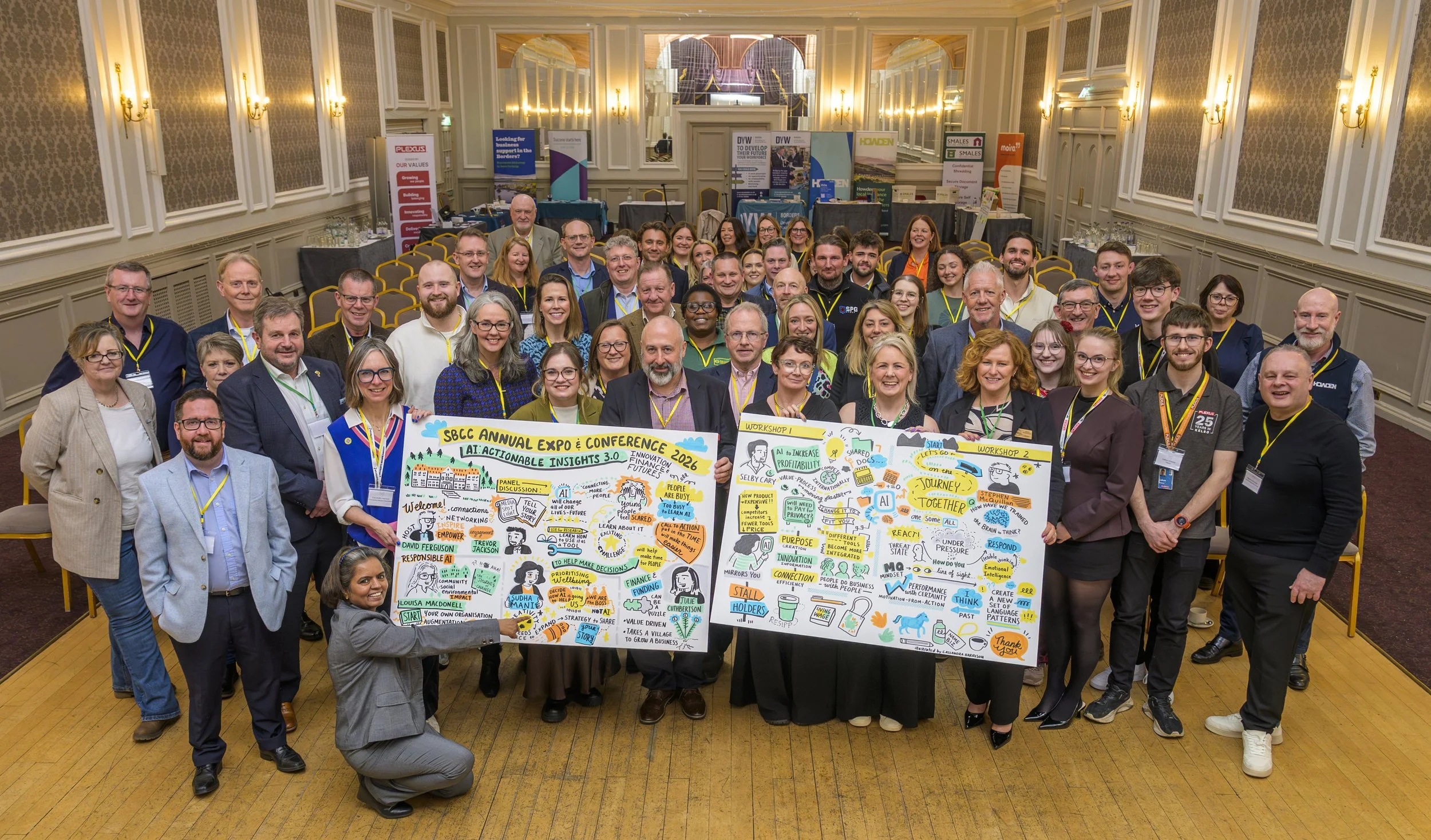 A goup of people looking happy towards the camera, holding up large illustrated boards created by UK based live illustrator Cassandra Harrison