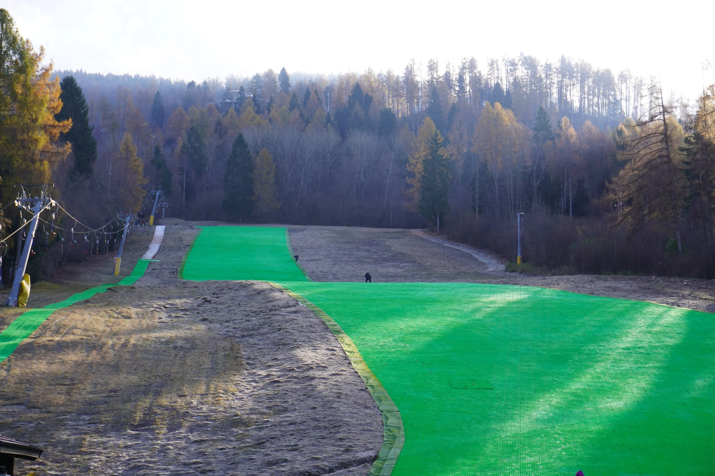 Una pista da sci artificiale e un impianto di risalita in un bosco.