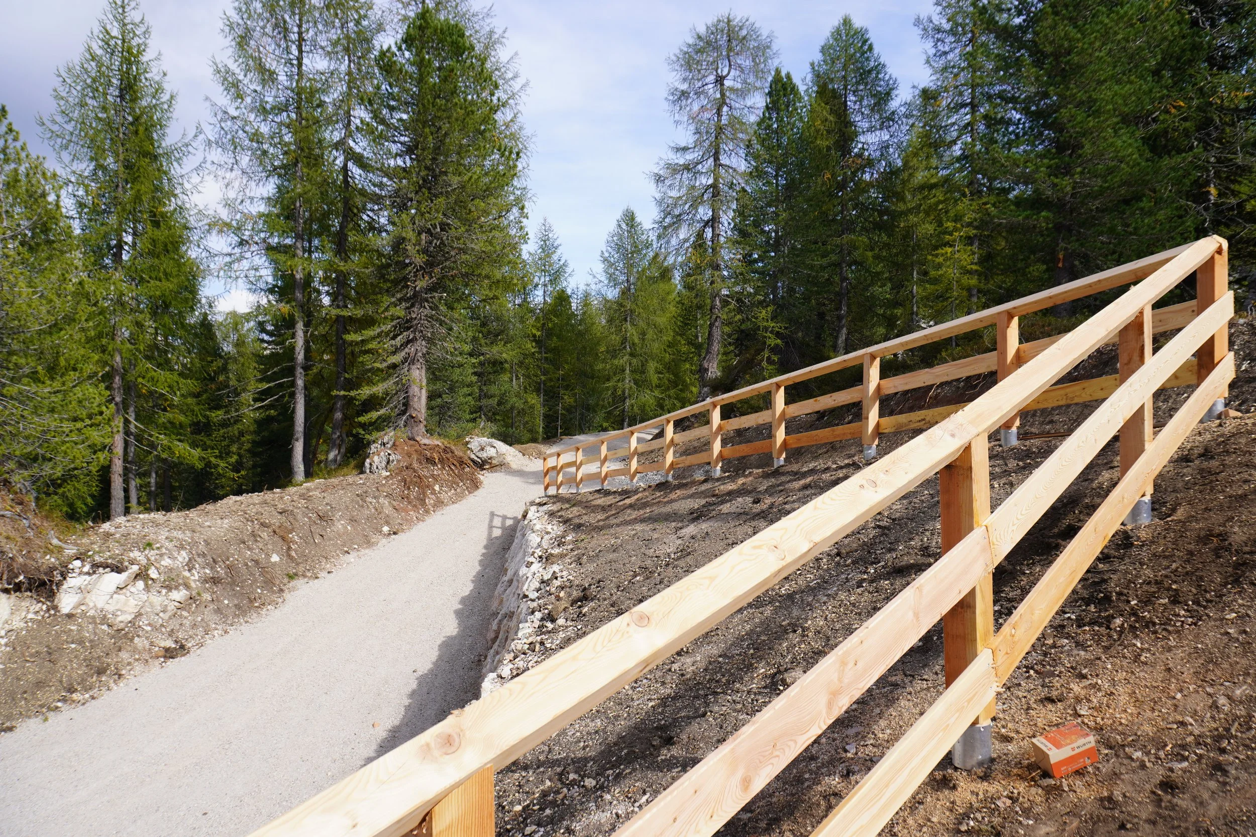 Sentiero in montagna con una ringhiera di legno lungo il bordo.