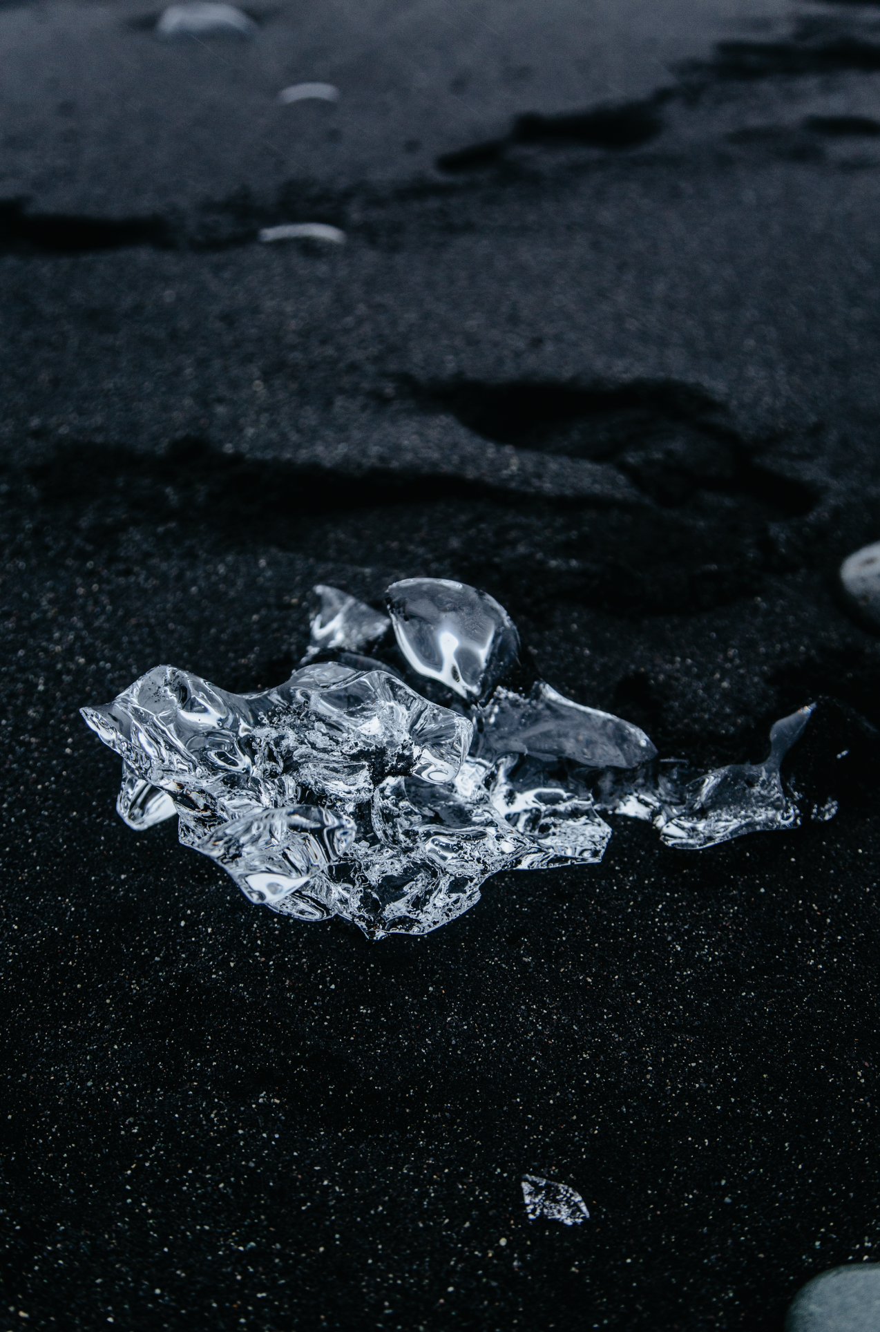 Photographie still life et abstraite par Mélissa Pottier. Morceaux de glace translucides sur une surface noire, composition épurée et graphique.