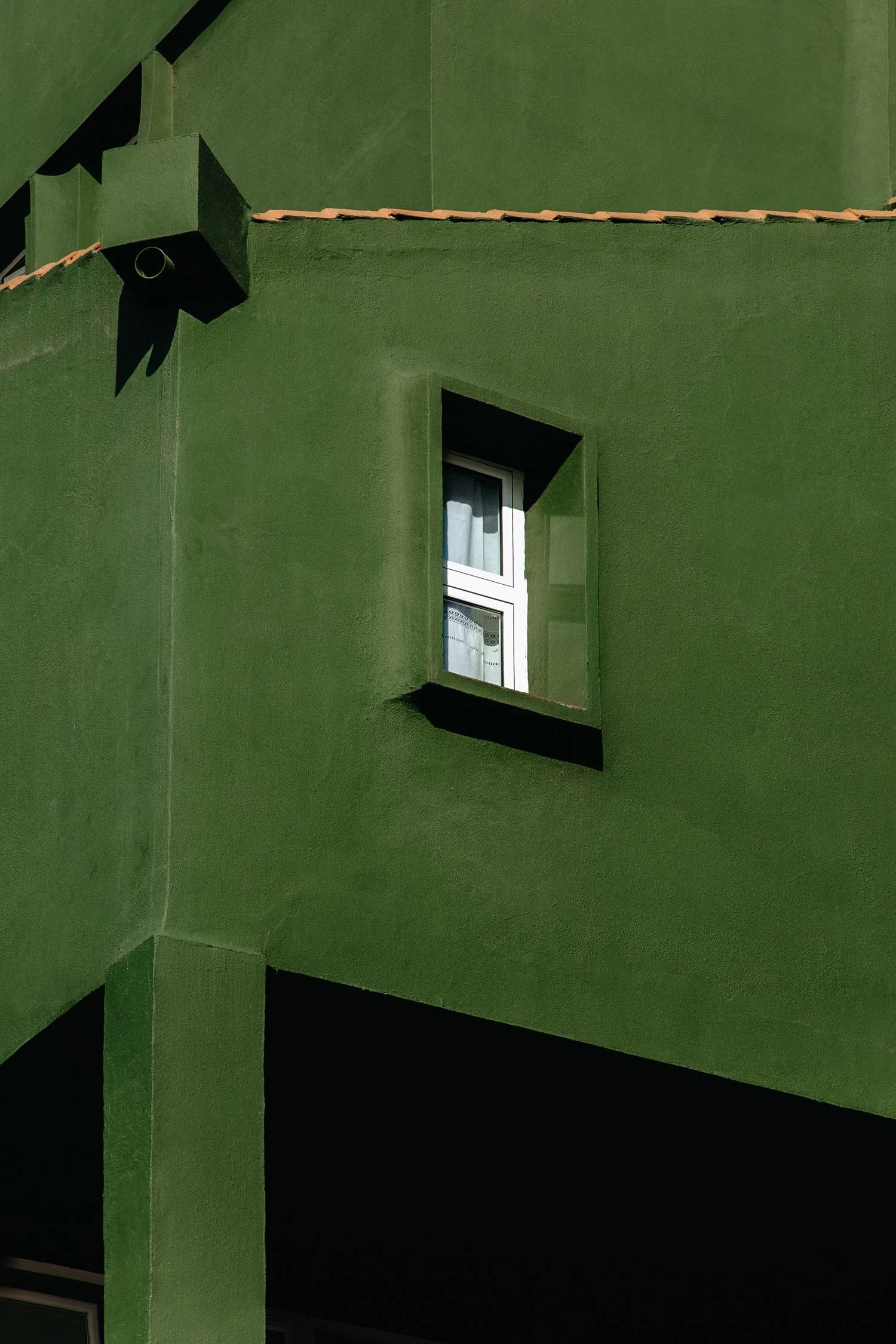 Photographie architecturale par Mélissa Pottier. Façade verte d'un bâtiment avec encadrement de fenêtre noir, composition géométrique et chromatique forte.