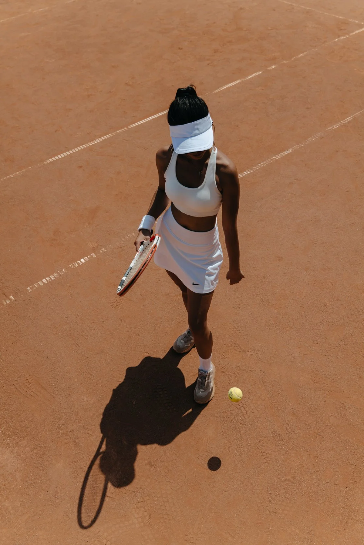 Joueuse de tennis en tenue blanche vue du dessus sur terrain ocre, photo sport par Mélissa Pottier photographe Paris