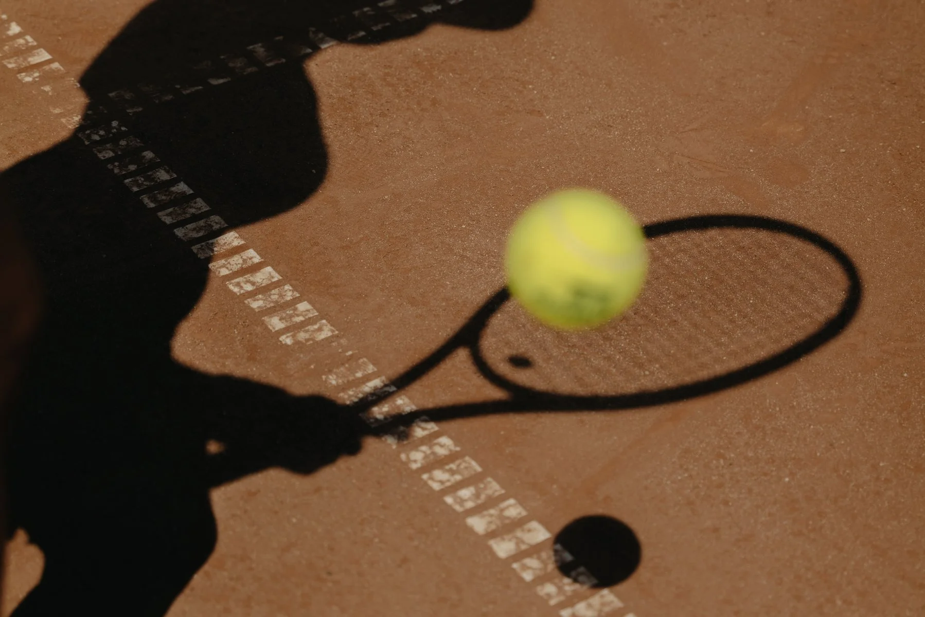 Photographie still life et sportive par Mélissa Pottier. Vue aérienne d'une raquette et d'une balle de tennis avec son ombre, composition minimaliste et graphique.