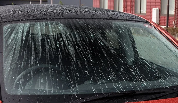 Voorruit van een auto met waterdruppels die afparelen na het aanbrengen van een glascoating