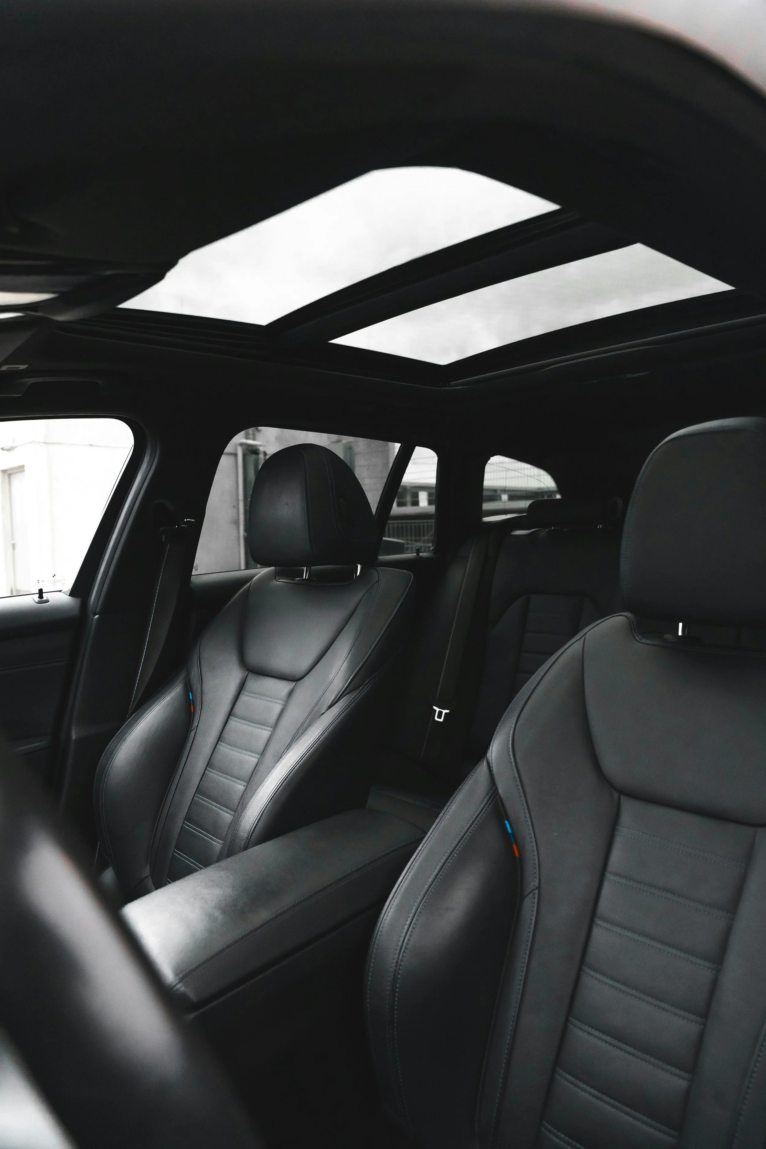 Interieur van een moderne auto met zwarte leren stoelen en een glazen panoramadak.