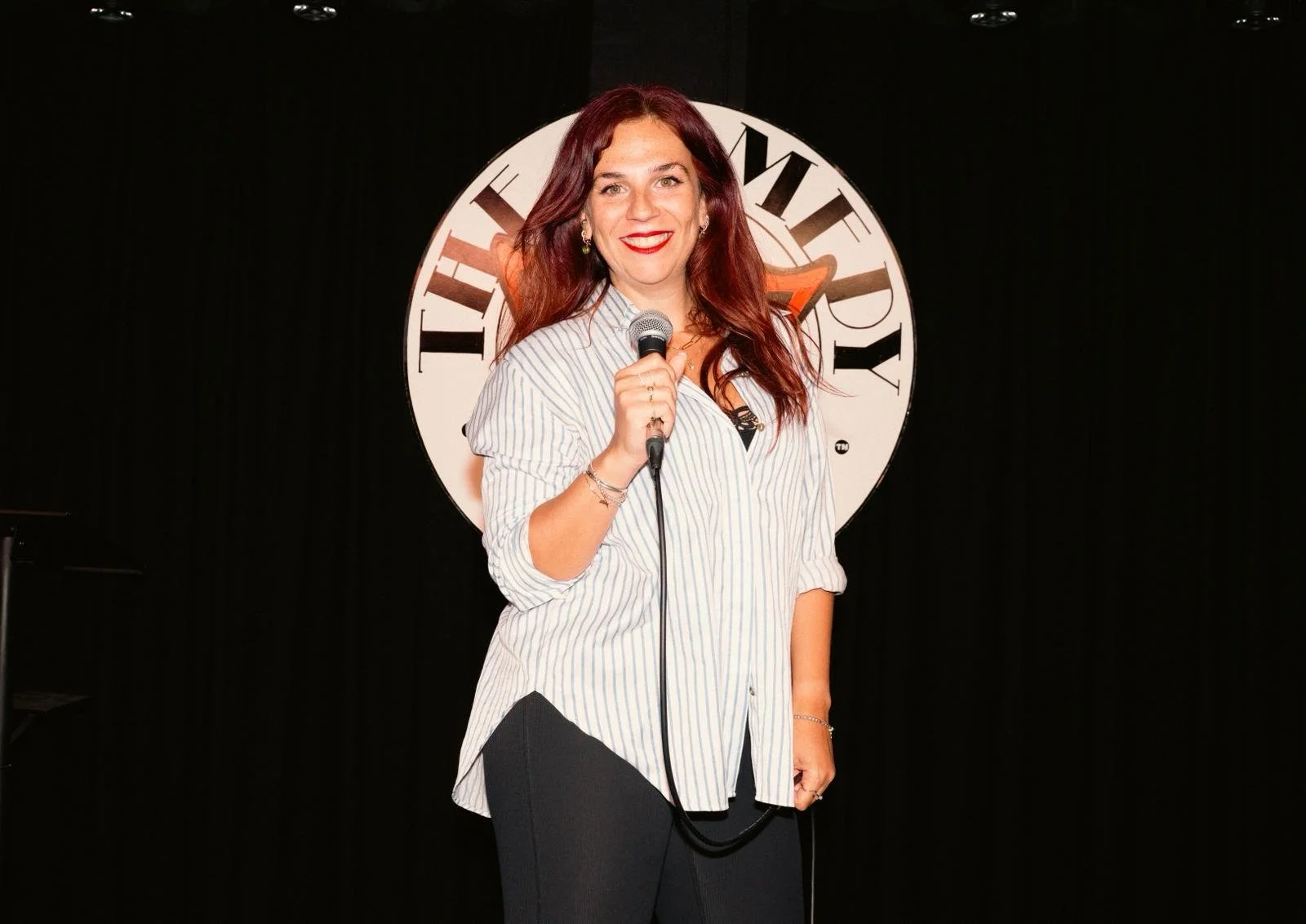 A woman with red hair holding a microphone
